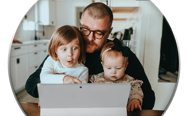 Family of 3 sitting at table looking at laptop