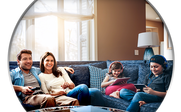 Family of 4 on the couch with devices and popcorn
